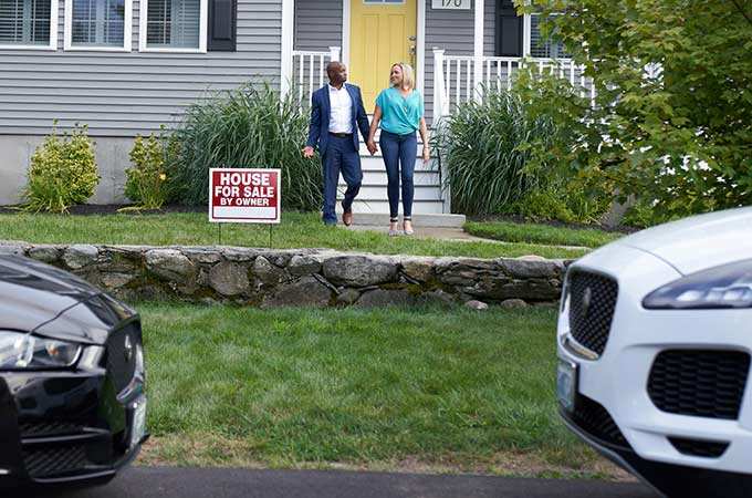 Kara and John walk in front of an available real estate property.