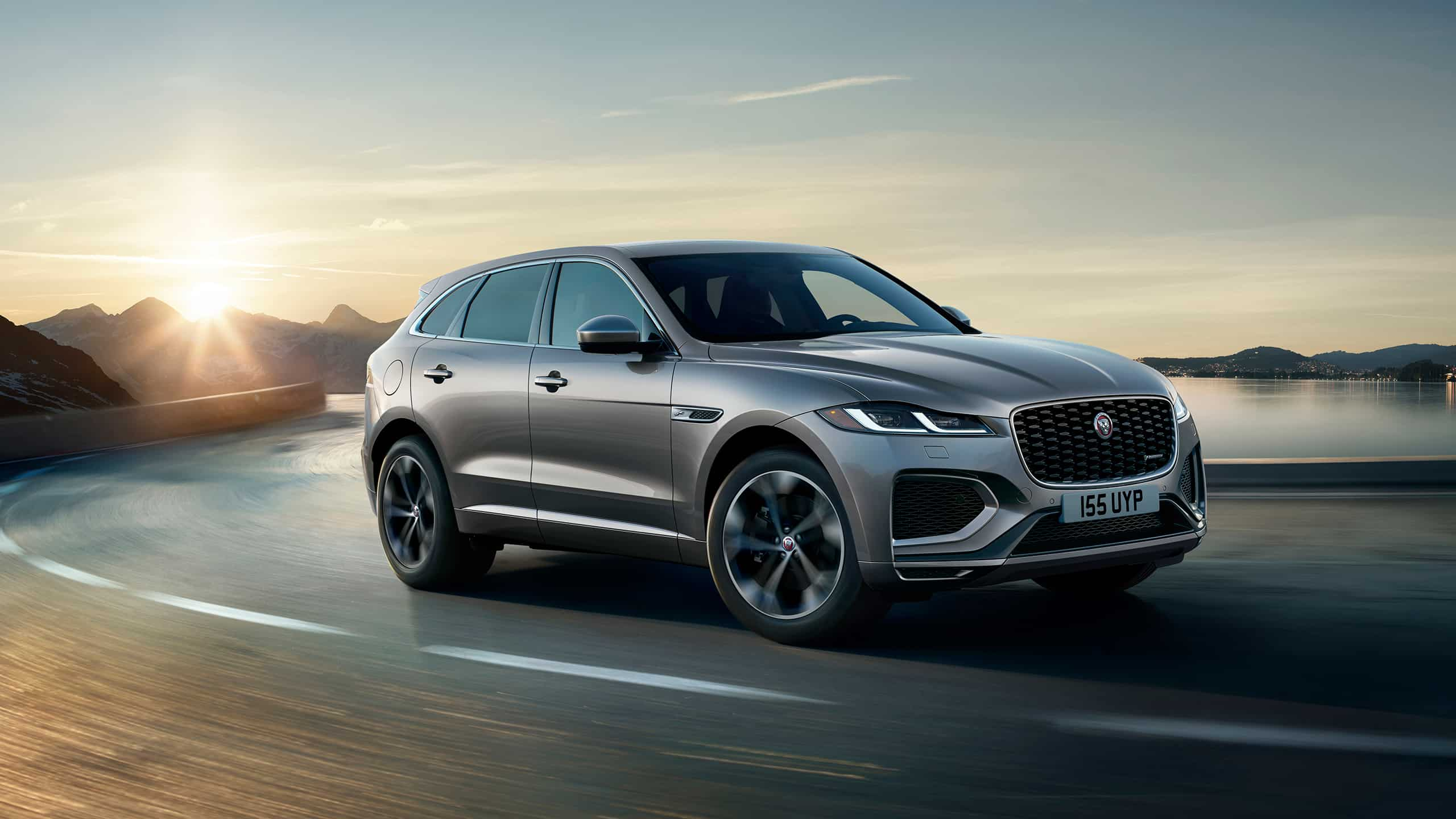 F-PACE running on river side road surrounded by mountains 